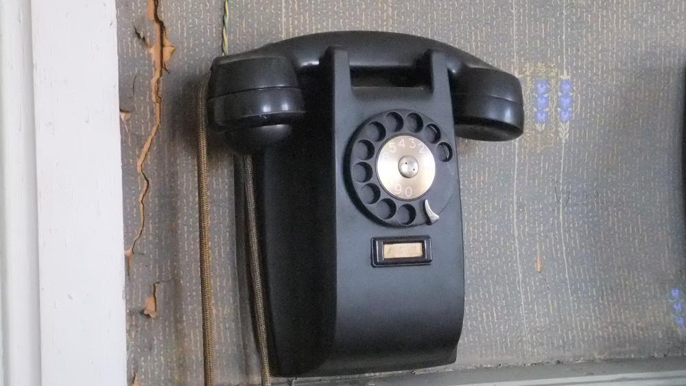 Vanha musta puhelin kiinnitetty seinälle.